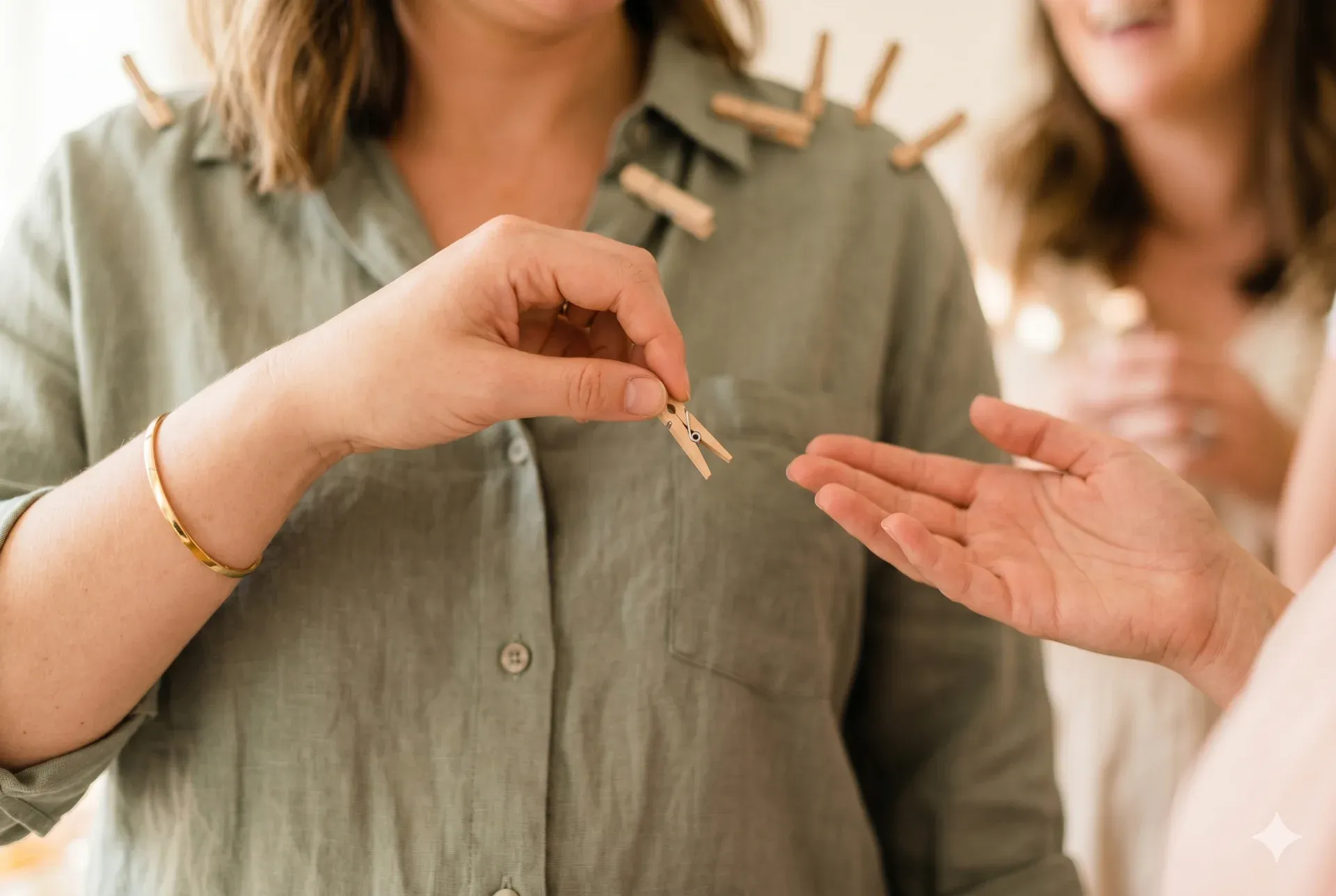A hand lifting a clothespin off another guest's shirt — the steal moment in Don’t Say "Baby"